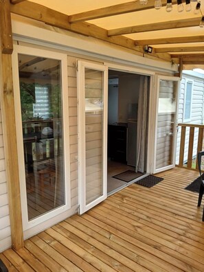 En træterrasse med en skydedør, der fører til et køkkenområde.