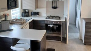Een moderne keuken met een centraal eiland, een ingebouwde magnetron, gasfornuis en een koffiezetapparaat.