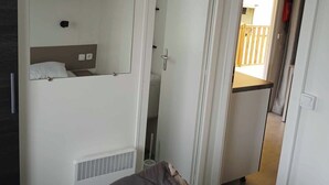 Een slaapkamer met een bed, een kledingkast en een badkamer, zichtbaar door een geopende deur.
