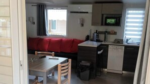 Een knus woongedeelte met een eethoek, kitchenette en een rode bank.