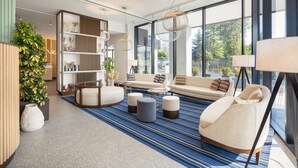 A modern living room with a sofa set, ottomans, a coffee table, and a bookshelf. - Courtyard By Marriott Milano Linate (Milan)