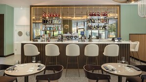 A bar area with a counter, bar stools, and shelves stocked with bottles. - Courtyard By Marriott Milano Linate (Milan)