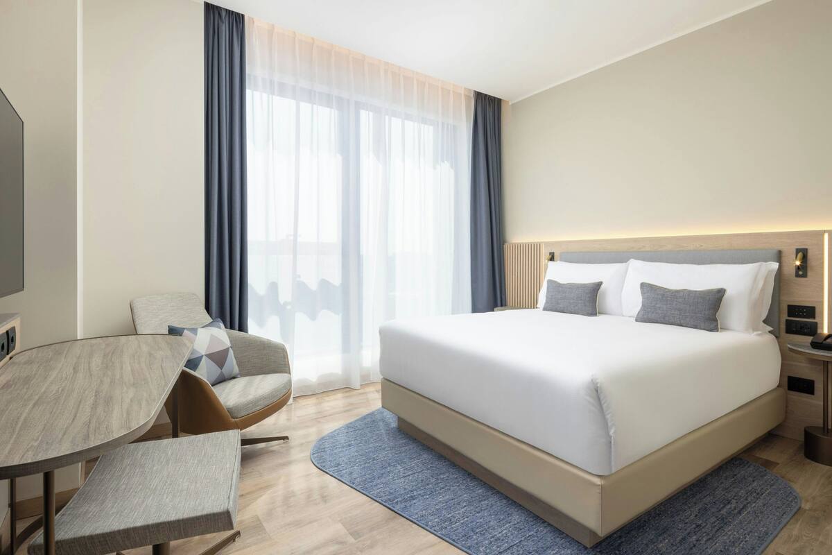 Una camera d'albergo moderna con un letto grande, una scrivania e una sedia.