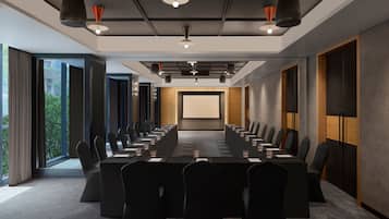 A conference room with a long table, chairs, and a projector screen.