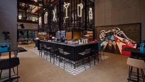 Un área de bar moderna con un letrero de neón, un mural y una barra con taburetes.