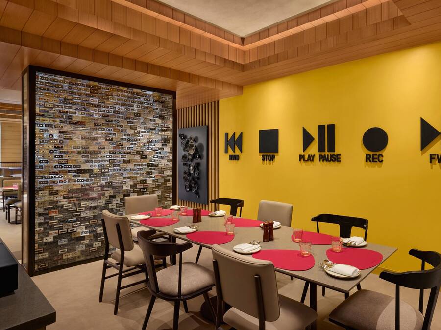 A conference room with a yellow wall, a wall clock, and a red tablecloth.