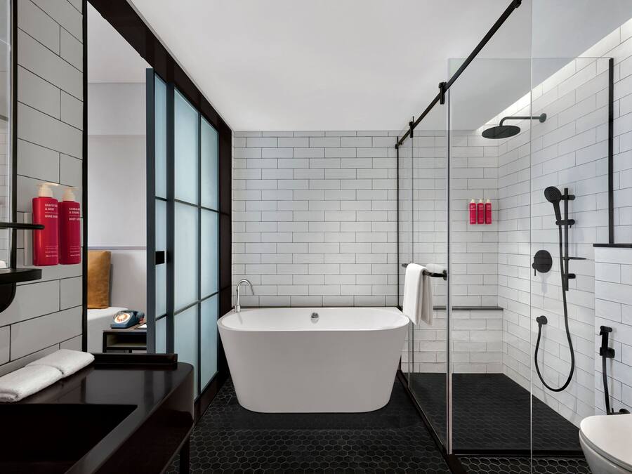 A modern bathroom with a freestanding bathtub, a glass-enclosed shower, and a black countertop with a sink and mirror.