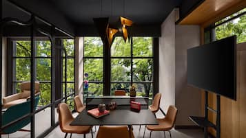 A modern dining area with a large table, chairs, and a TV screen.