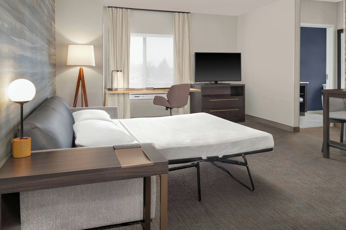 Une chambre d’hôtel équipée d’un lit, d’un bureau, d’une chaise, d’une télévision et d’une lampe.