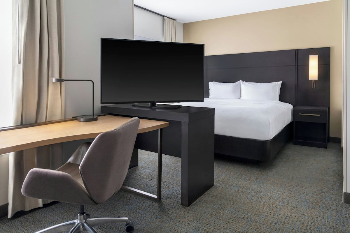 Une chambre d’hôtel comprenant un lit, un bureau avec une chaise, une télévision et une table de chevet.