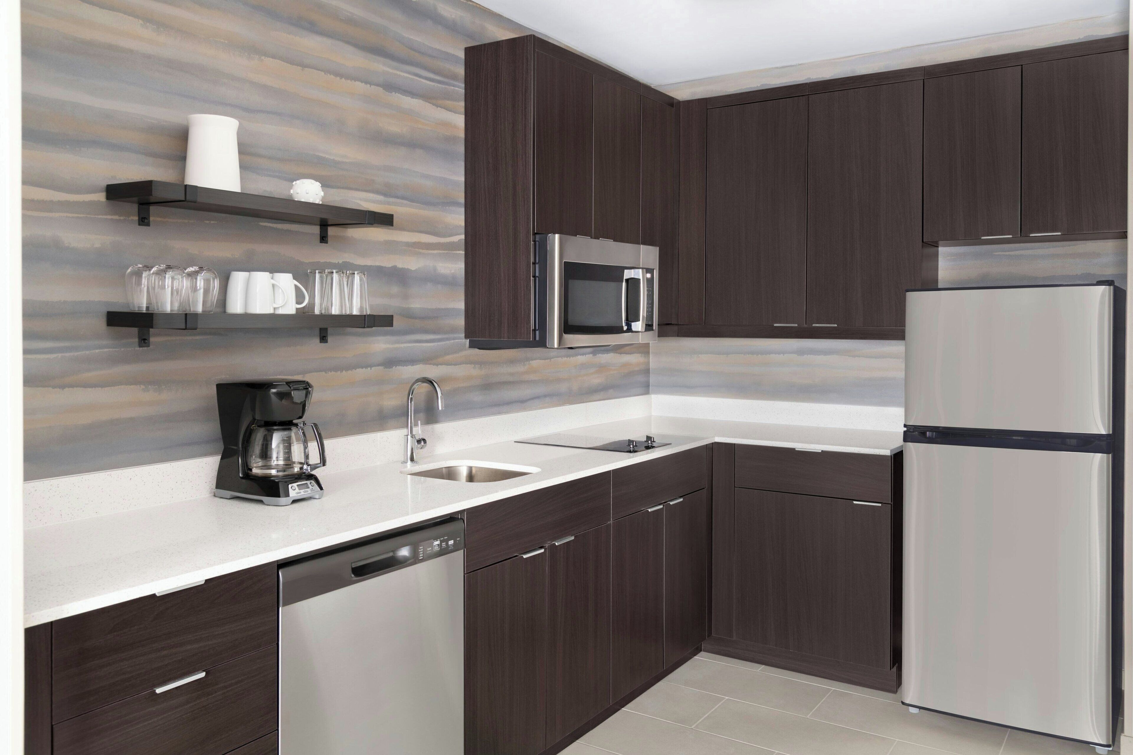 Una cocina moderna con armarios de madera oscura, electrodomésticos de acero inoxidable y una salpicadera de mármol.