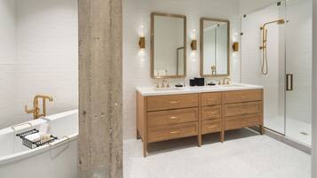A modern bathroom with a double sink vanity, a bathtub, and a glass-enclosed shower.