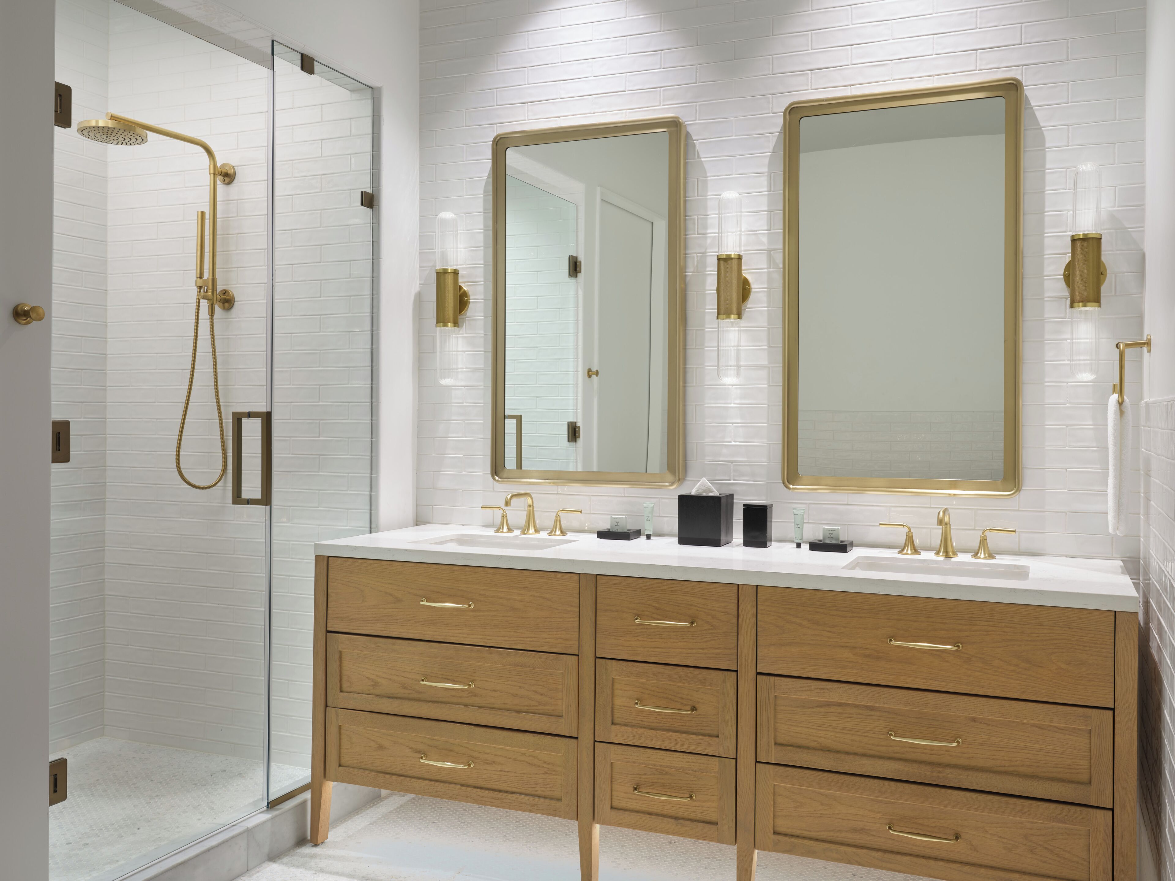 A modern bathroom with a walk-in shower, two large mirrors, and a vanity with multiple drawers.