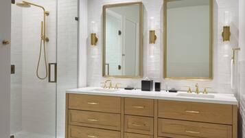 Un baño moderno con cabina de ducha a ras de suelo, dos espejos grandes y un mueble de tocador con varios cajones.
