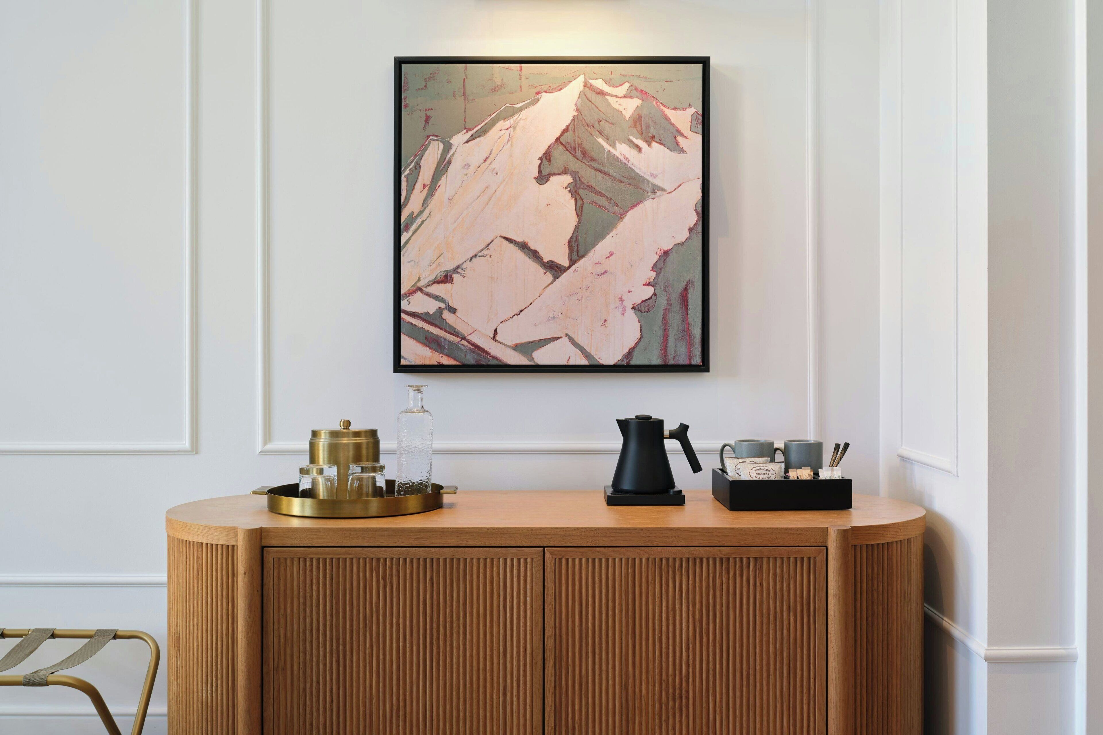A wooden reception desk with a framed abstract painting above it.