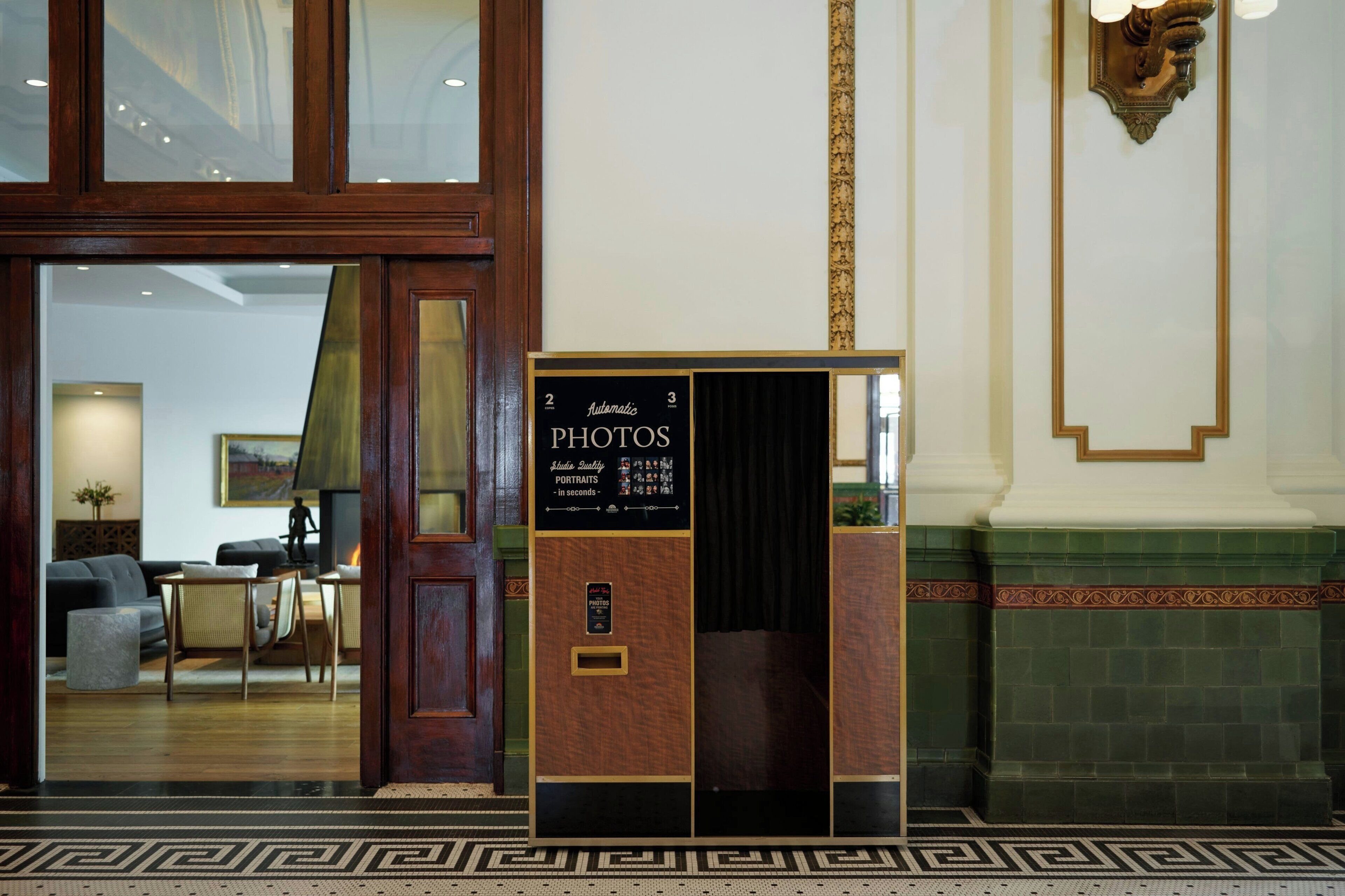 A reception area with a wooden door, a signboard for photos and portraits, and a green tiled wall.