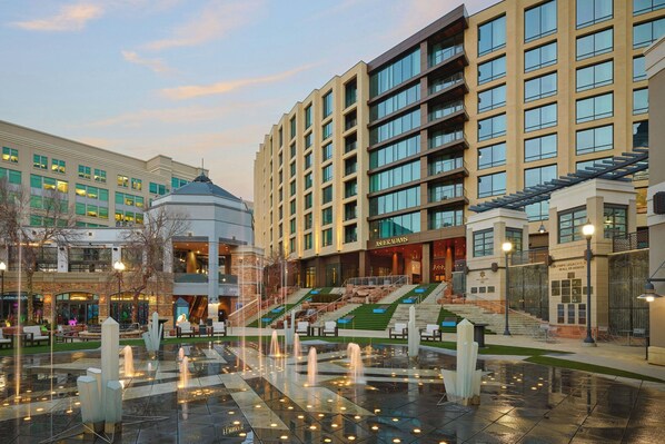 A hotel with a central courtyard featuring a fountain, surrounded by modern buildings with multiple floors and balconies. - Asher Adams, Autograph Collection (Salt Lake City)