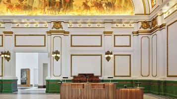 A grand lobby with a wooden reception desk, ornate wall decorations, and a large mural on the ceiling.