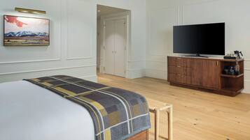 A bedroom with a bed, a television on a wooden cabinet, and a painting on the wall.