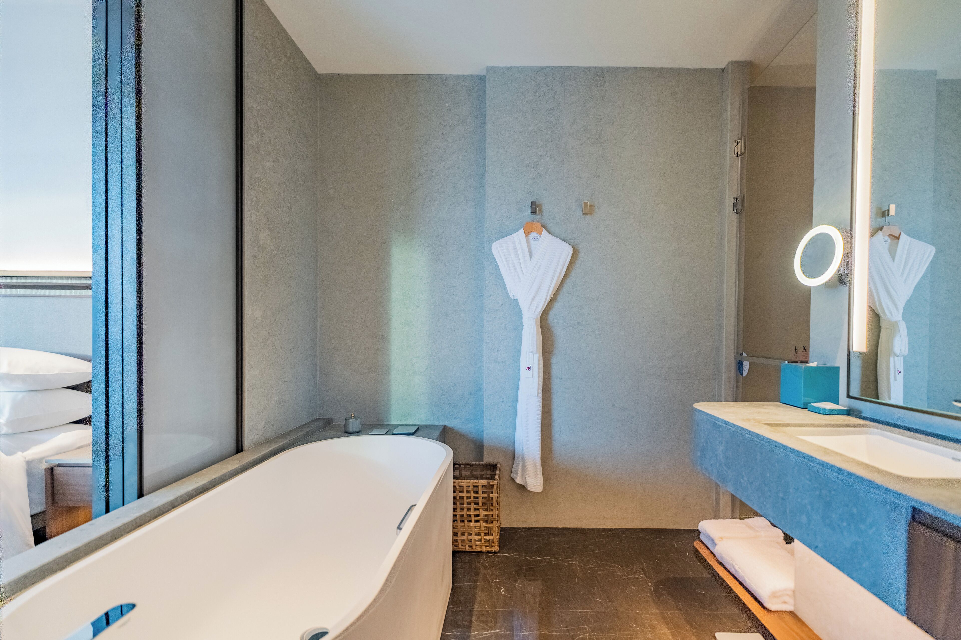 Un baño moderno con una bañera independiente, un espejo grande con luz de aro y un perchero para toallas.