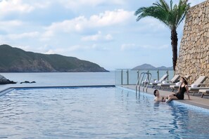 A pool with a view of the sea and mountains, a palm tree, and lounge chairs. - Zhuhai Dong'Ao Island Marriott Resort And Spa (Zhuhai)