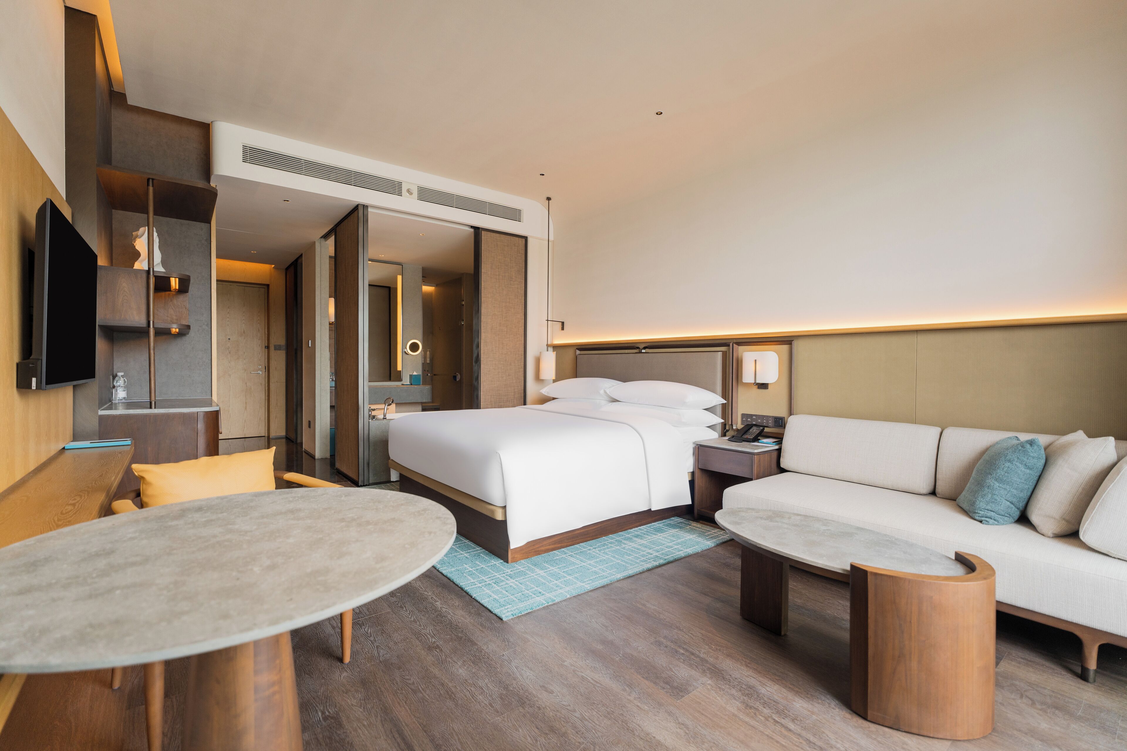 A modern hotel room with a bed, sofa, and a small table.