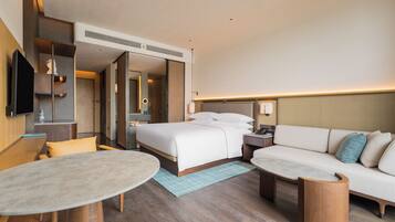 A modern hotel room with a bed, sofa, and a small table.