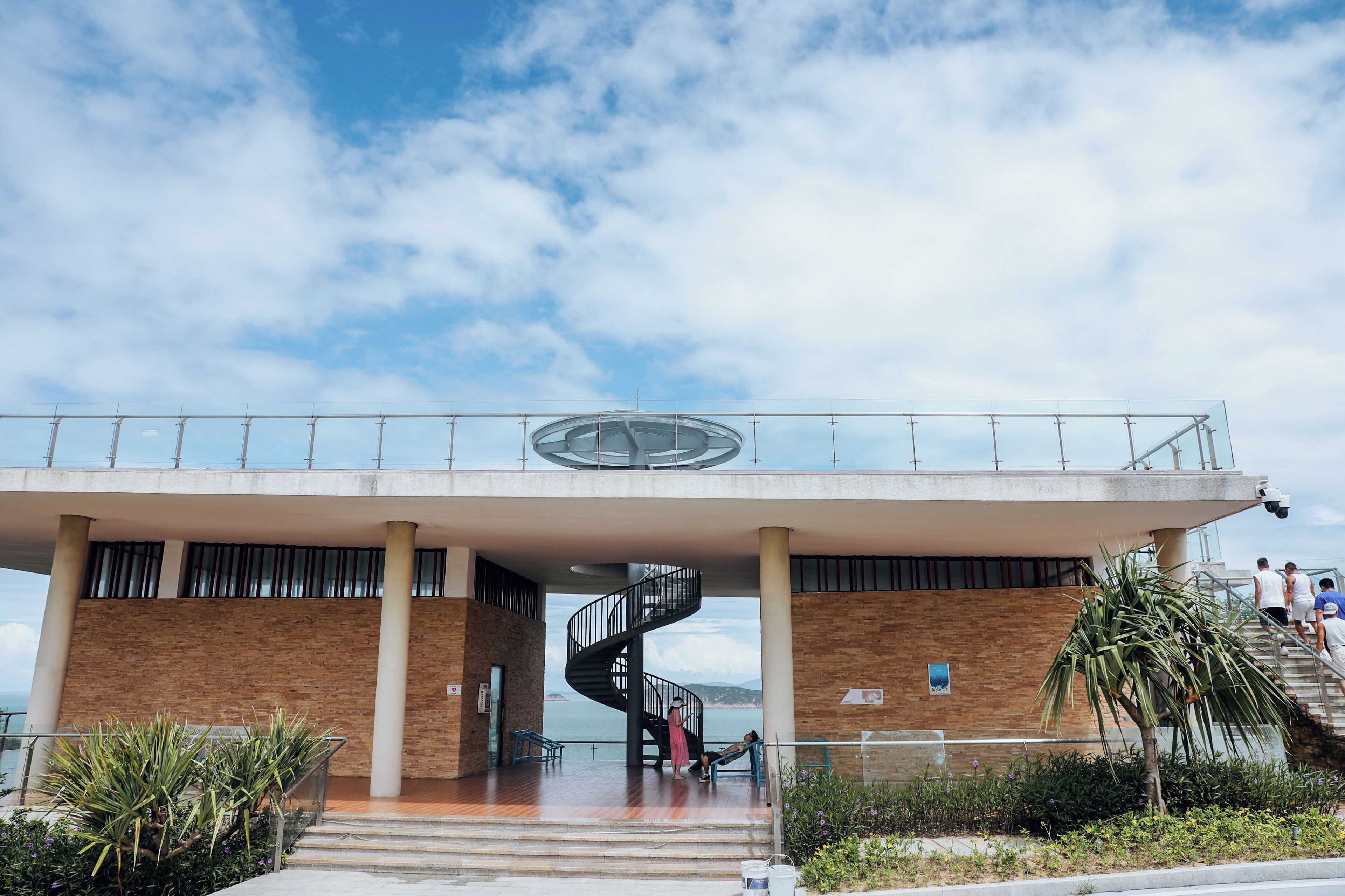 A modern building with a spiral staircase, a balcony, and a view of the sea.