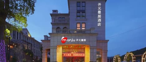 A hotel with a prominent entrance, a sign with Chinese characters, and a well-lit facade.
