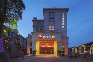 A hotel with a prominent entrance, a sign with Chinese characters, and a well-lit facade. - Manju Hotel (Kuantang) (Haining)