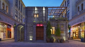 A hotel with a stone facade, arched entrance, and a covered outdoor seating area. - Manju Hotel (Kuantang) (Haining)