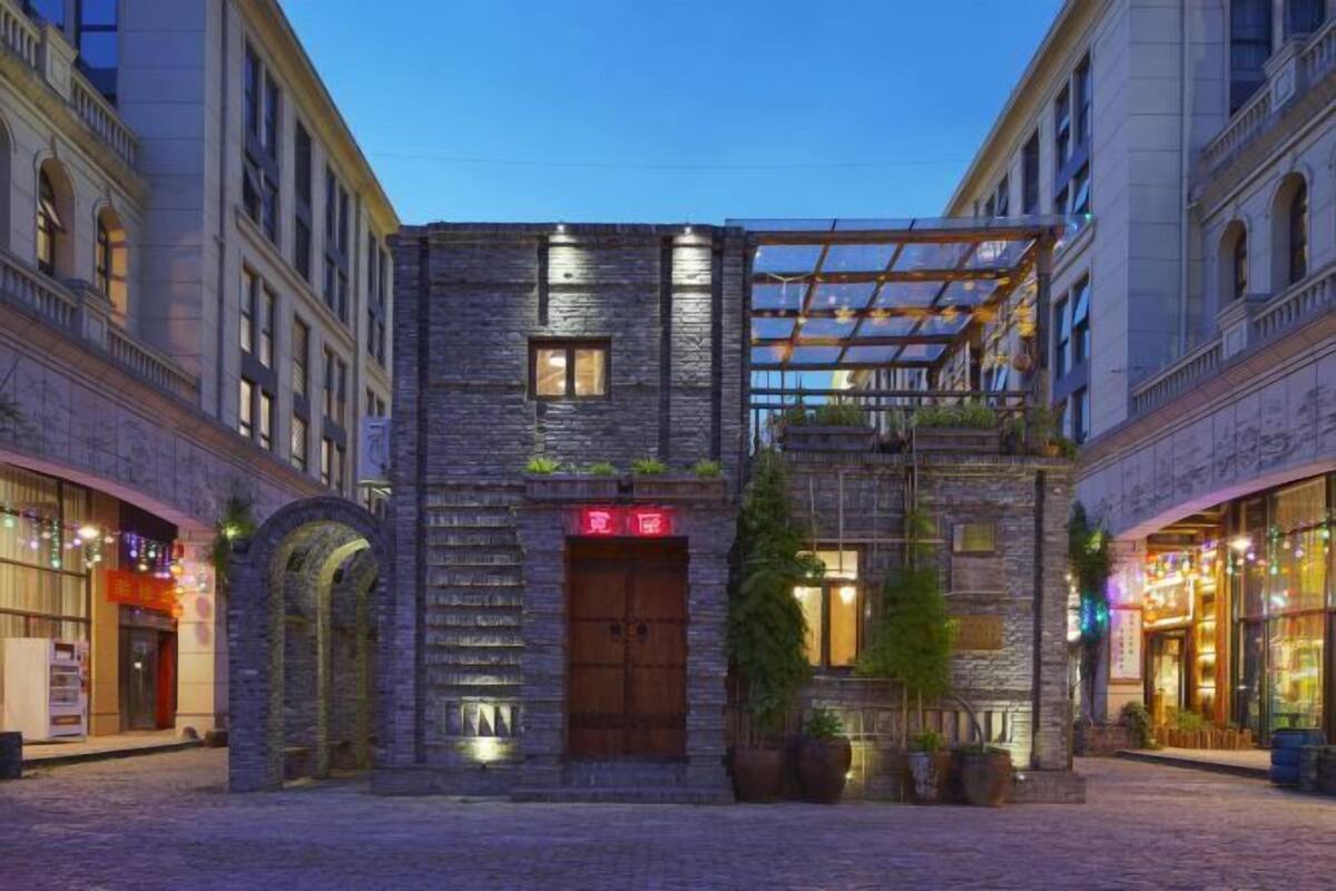 Un hotel con facciata in pietra, ingresso ad arco e una zona salotto esterna coperta.