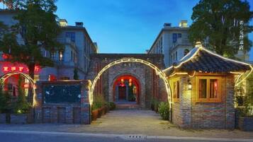 A traditional Chinese building with a stone archway entrance, a small pavilion, and a signboard.