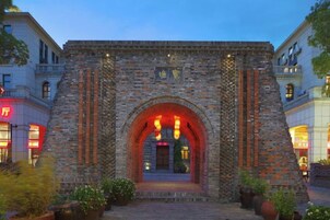 Un arco de piedra marca la entrada a un edificio, con un camino pavimentado que lo conduce.