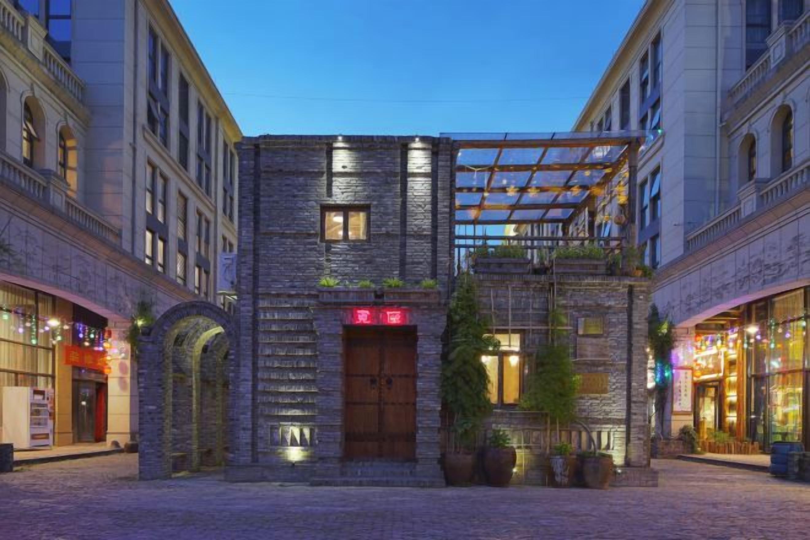 A building with a stone facade, a wooden door, and a balcony with plants.