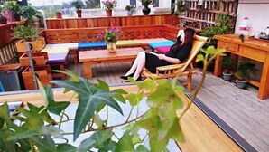 A wooden deck with a seating area, including a bench and a table with a vase of flowers. - Manju Hotel (Kuantang) (Haining)