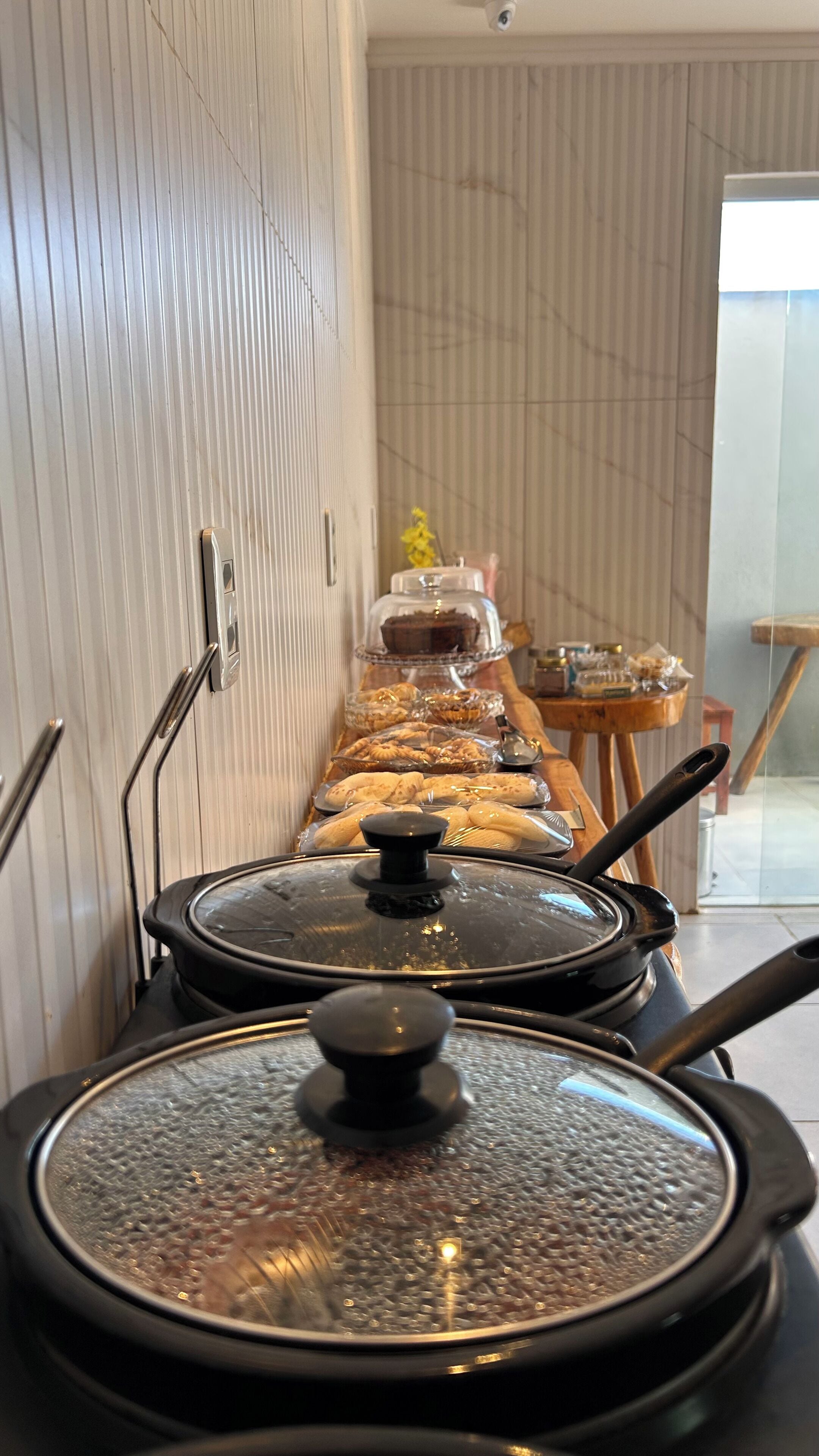 A kitchen area with a long counter displaying various food items and covered cooking pots.