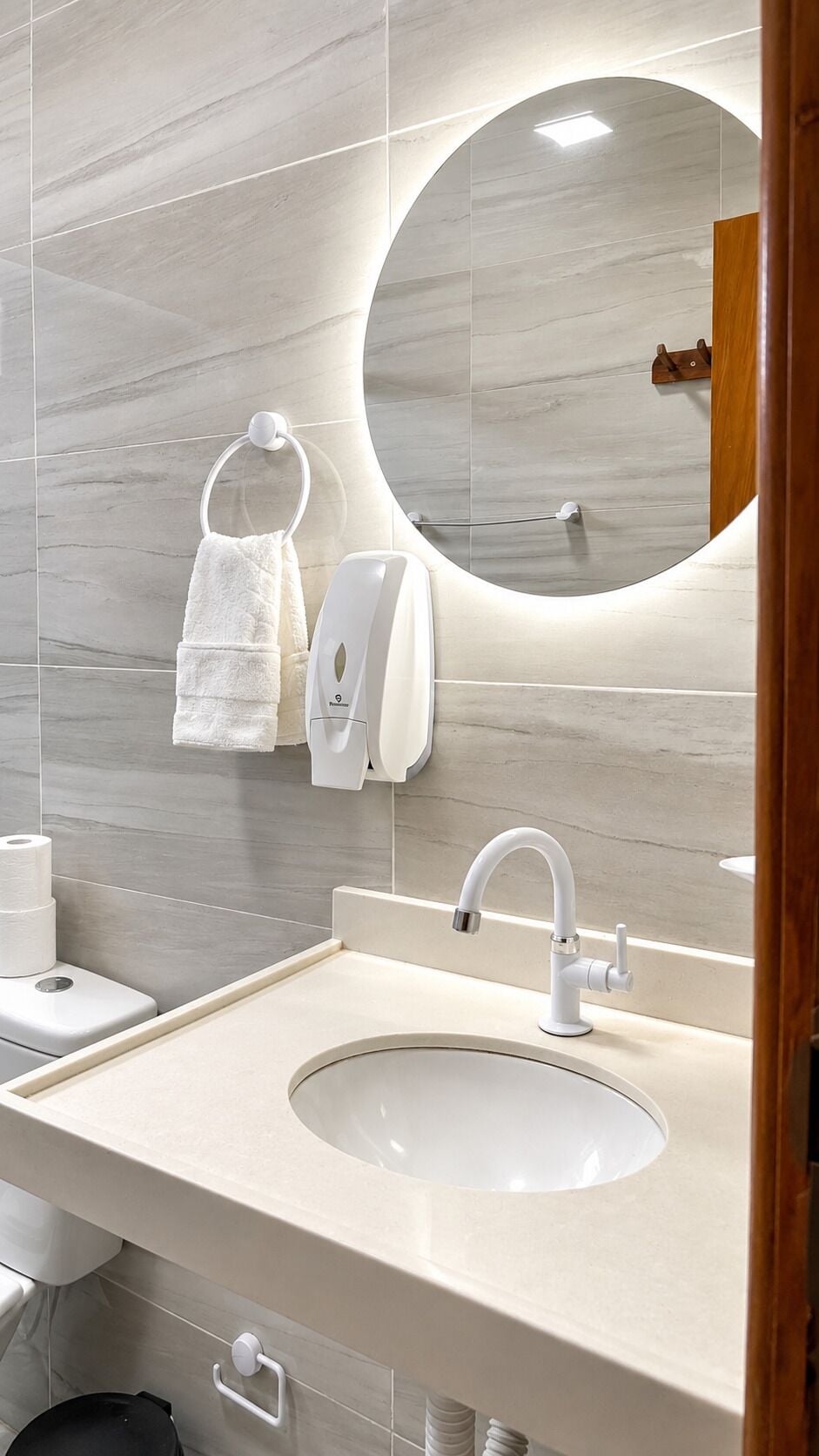 A bathroom with a sink, mirror, towel rack, toilet, and hand dryer.