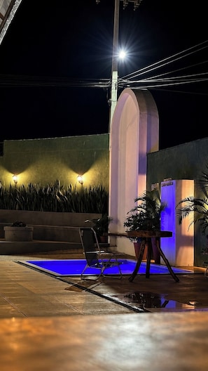 A nighttime outdoor area with a pool, a metal structure, and a wall with plants. - Pousada Coco Babaçu (Vicosa do Ceara)