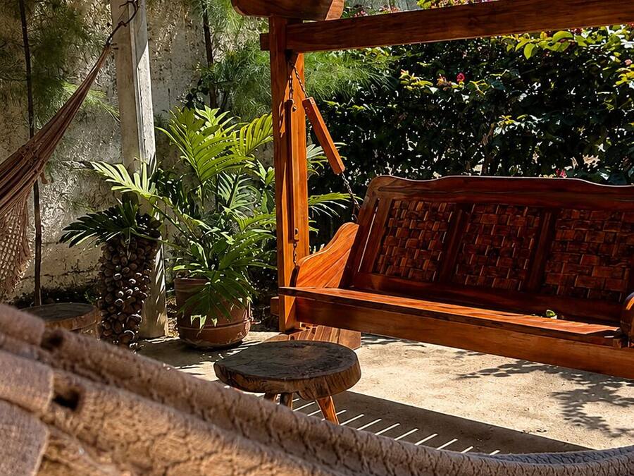 Eine Hängematte, eine Holzbank und Kübelpflanzen unter einer Holzpergola.