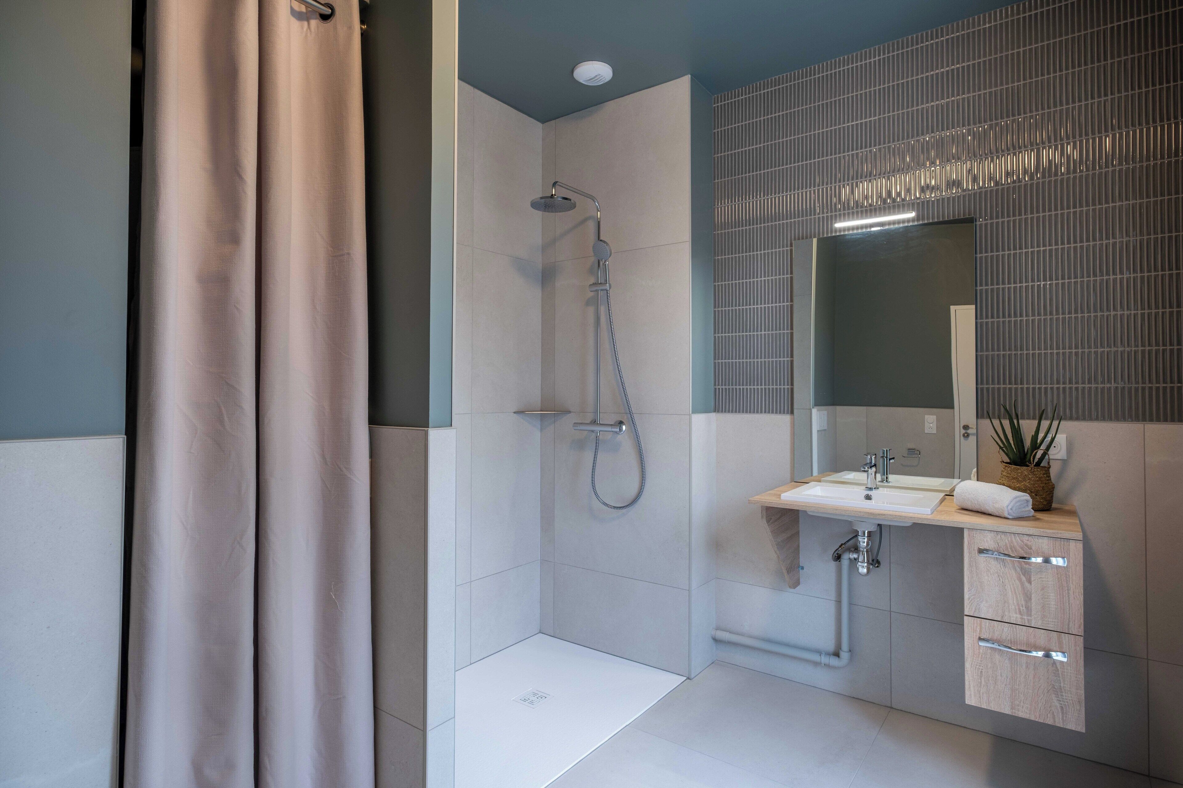 A modern bathroom with a shower, sink, and mirror.