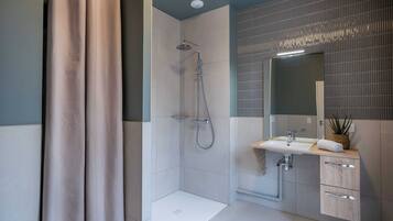 A modern bathroom with a shower, sink, and mirror.
