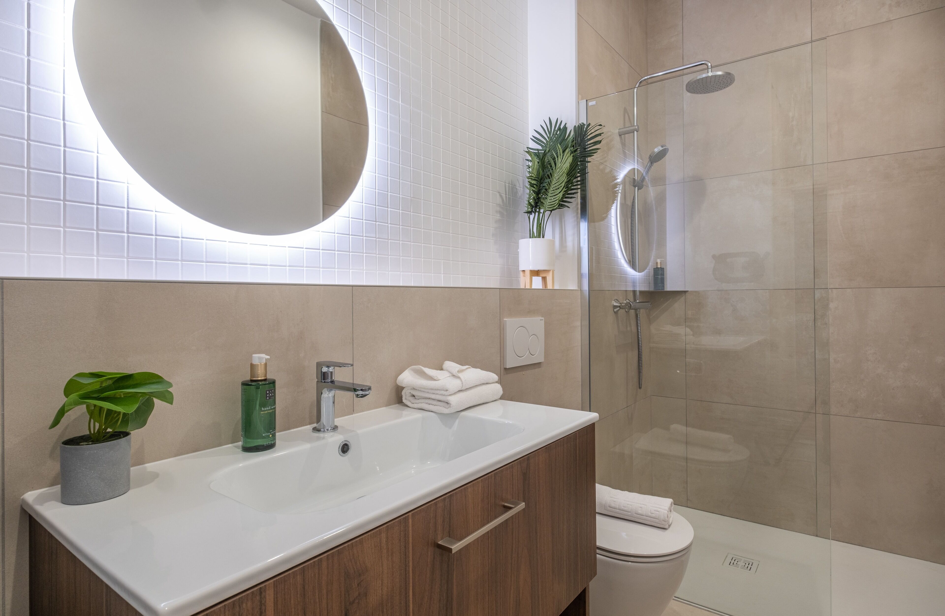 Une salle de bain moderne avec un grand lavabo, un miroir et une douche.