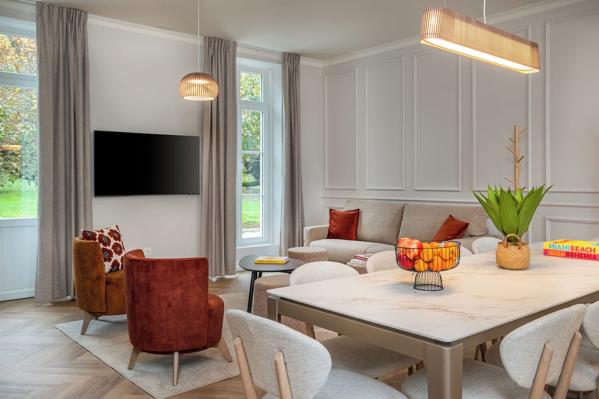 A modern living room with a flat-screen TV, a dining table, and comfortable seating.
