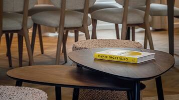 A modern dining area with a round table, four chairs, a potted plant, and a hanging light fixture.