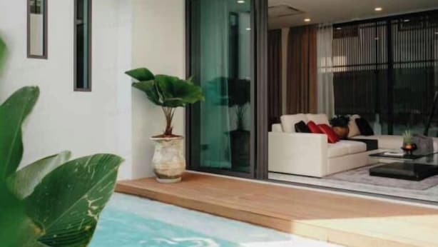 Una sala de estar moderna con pared de vidrio, un sofá blanco y una mesa de centro.