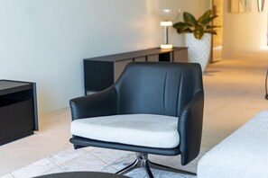 Uma cadeira moderna com assento e encosto acolchoados, sobre um piso de azulejos em um ambiente com design minimalista.