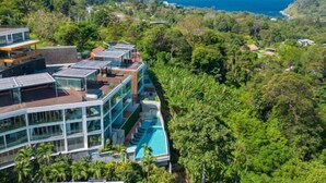 Un resort moderno con piscina, habitaciones de paredes de vidrio y vista al océano.