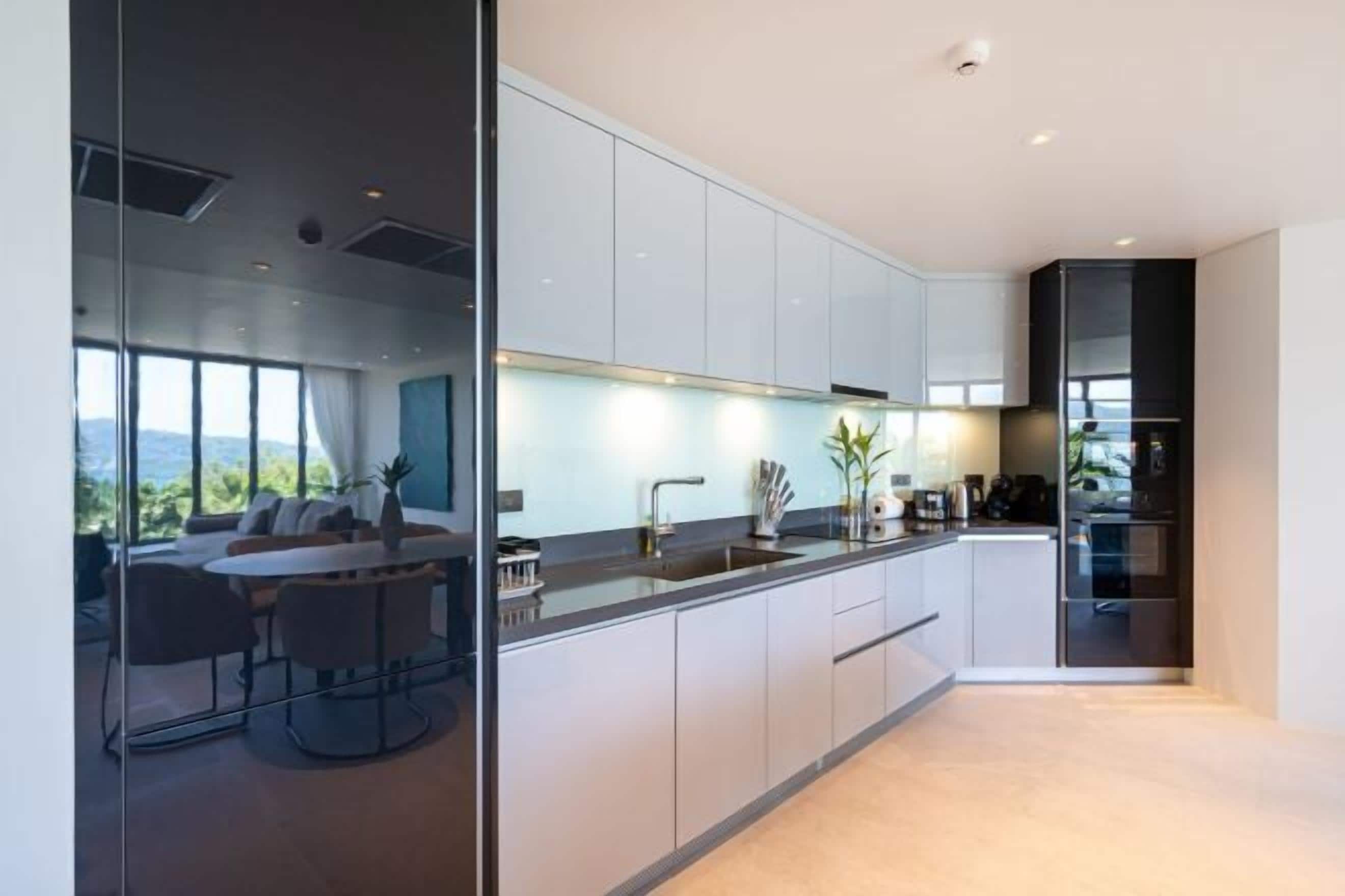 A modern kitchen with white cabinets, a black countertop, and a built-in oven.