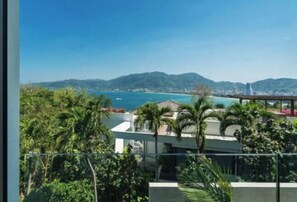 A coastal view with a modern building, palm trees, and a clear sky.